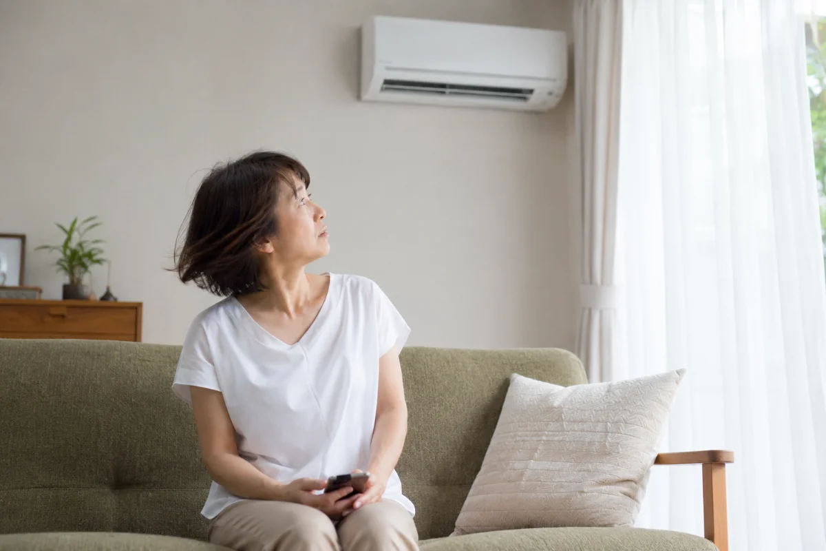 ソファに座り、エアコンからの風の臭いを気にして振り返る女性