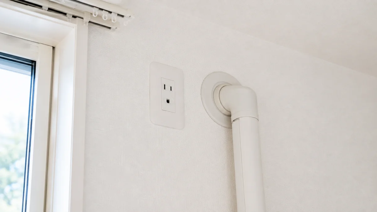 住宅の壁にあるエアコン用コンセントと配管穴のクローズアップ